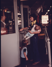 72. Mother with Her Children at the Cashier's Window Paying for Her Annual Sticker after Her Car Had Successfully Passed Testing at an Auto Emission Inspection Station in Downtown Cincinnati, Ohio, 09/1975. Photographer: Lyntha Scott Eiler