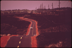 41. Highway 11 passing over 1868 lava flow near Waiohinu. Lava flows, as recent as 1973, have impaired the quality of the land for agricultural use. Devastated trees can be seen in the background, November 1973. Photographer: Charles O'Rear